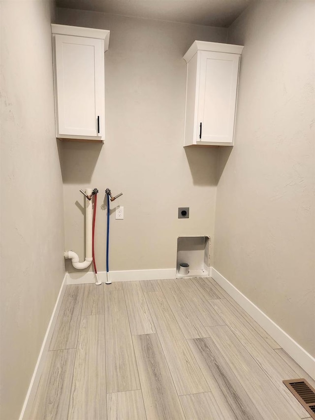 laundry area with hookup for an electric dryer, washer hookup, light hardwood / wood-style floors, and cabinets