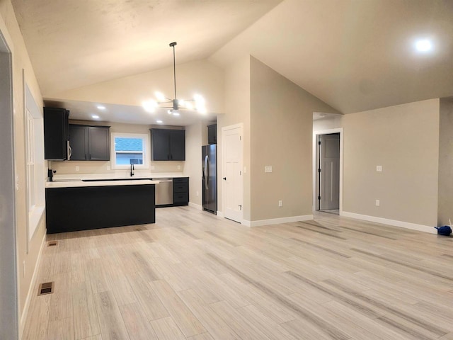 kitchen with stainless steel appliances, kitchen peninsula, pendant lighting, lofted ceiling, and light wood-type flooring