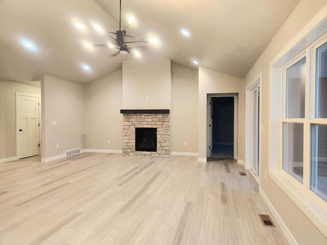 unfurnished living room featuring a stone fireplace, ceiling fan, light hardwood / wood-style floors, and vaulted ceiling