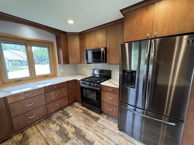 kitchen featuring wood-type flooring, backsplash, stainless steel appliances, and light stone counters