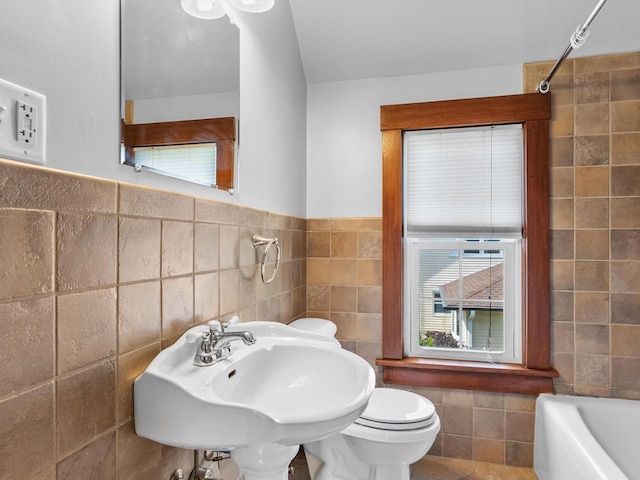 bathroom with sink, tile walls, and toilet