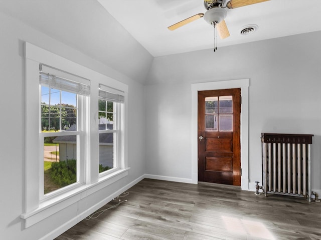 empty room with radiator heating unit, dark hardwood / wood-style flooring, vaulted ceiling, and ceiling fan