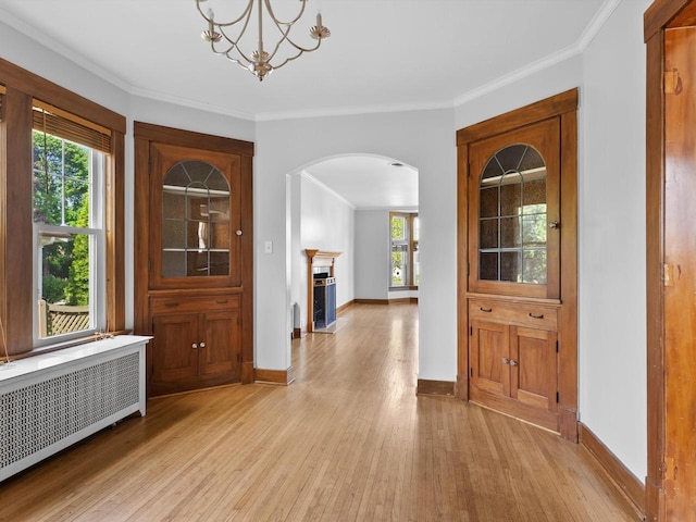 corridor with a chandelier, radiator heating unit, light hardwood / wood-style floors, and crown molding