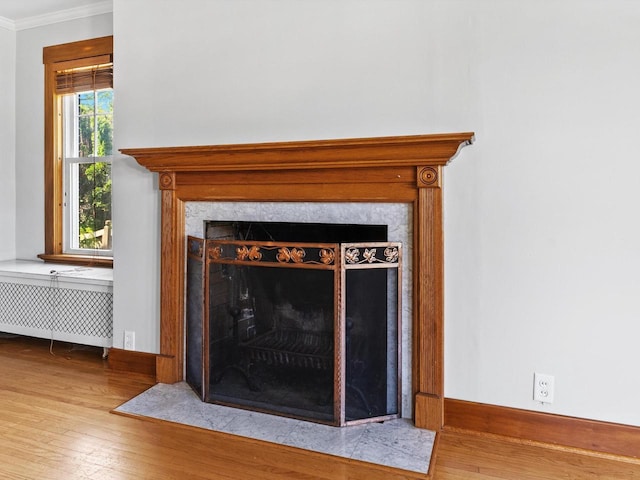 interior details with wood-type flooring, radiator heating unit, ornamental molding, and a premium fireplace