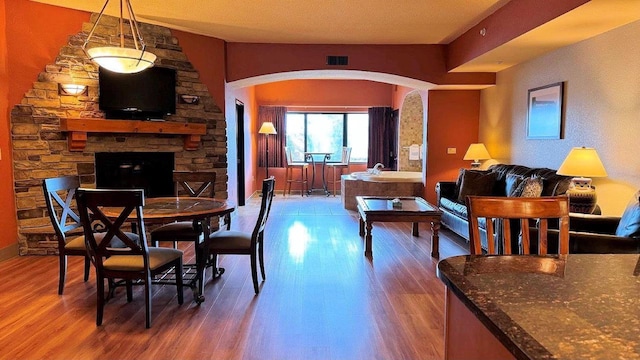 dining area with hardwood / wood-style flooring and a stone fireplace