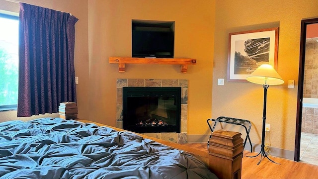 bedroom with a tile fireplace and hardwood / wood-style flooring