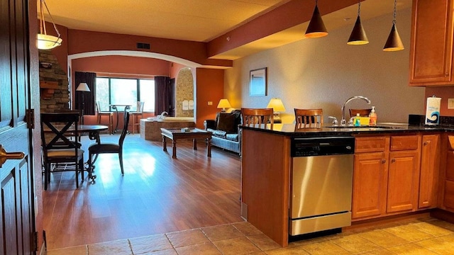 kitchen with stainless steel dishwasher, decorative light fixtures, sink, and light hardwood / wood-style flooring