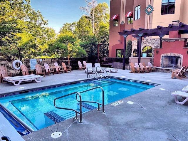 view of pool featuring an outdoor stone fireplace, a pergola, and a patio