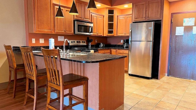 kitchen featuring kitchen peninsula, a breakfast bar, stainless steel appliances, sink, and hanging light fixtures