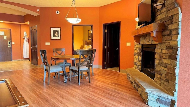 dining room featuring a fireplace, light wood-type flooring, and lofted ceiling