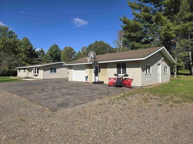 ranch-style home featuring a garage, an outbuilding, and a front lawn