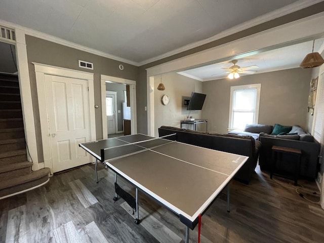 recreation room featuring ceiling fan, ornamental molding, and dark wood-type flooring