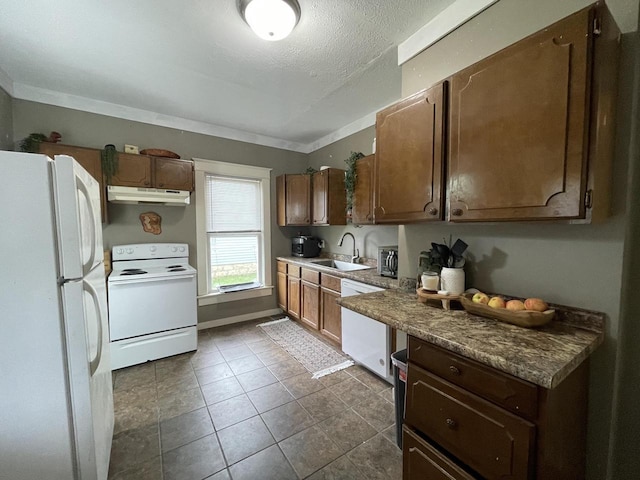 kitchen featuring a textured ceiling, white appliances, dark tile patterned flooring, and sink