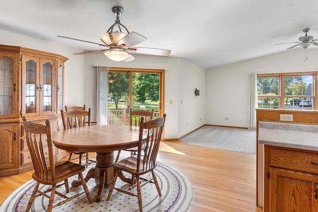 dining space with ceiling fan, a healthy amount of sunlight, lofted ceiling, and light hardwood / wood-style flooring