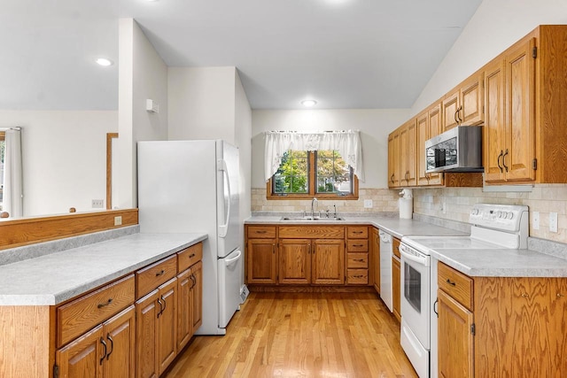 kitchen featuring lofted ceiling, white appliances, sink, light hardwood / wood-style flooring, and decorative backsplash