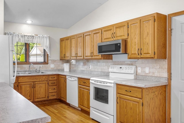 kitchen featuring tasteful backsplash, white appliances, sink, light hardwood / wood-style floors, and lofted ceiling