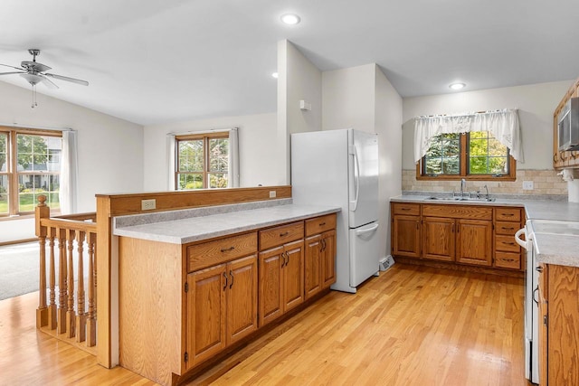 kitchen featuring kitchen peninsula, tasteful backsplash, sink, range, and white fridge