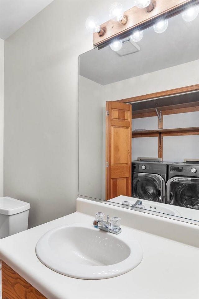 bathroom with washer and dryer, toilet, and vanity