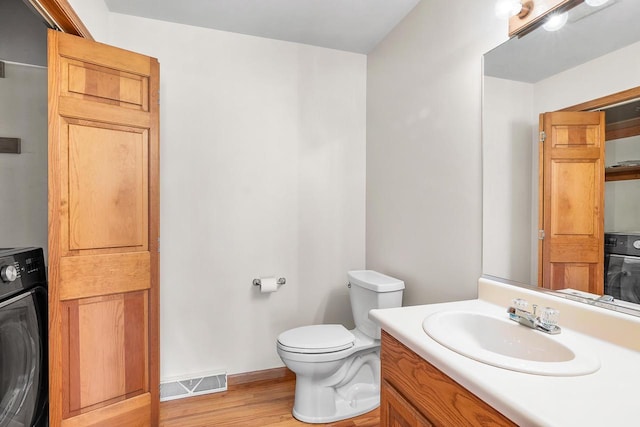 bathroom featuring hardwood / wood-style floors, vanity, toilet, and washer / clothes dryer