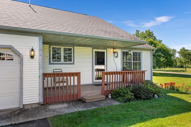 entrance to property with covered porch, a yard, and a garage