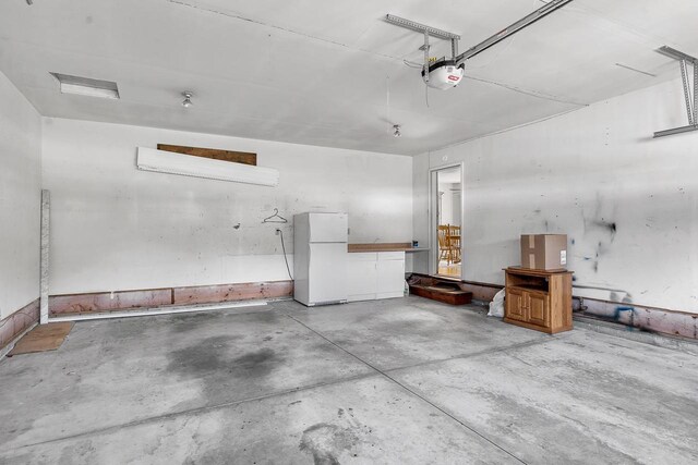 garage featuring white fridge and a garage door opener