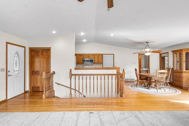 entrance foyer with light carpet, ceiling fan, and vaulted ceiling