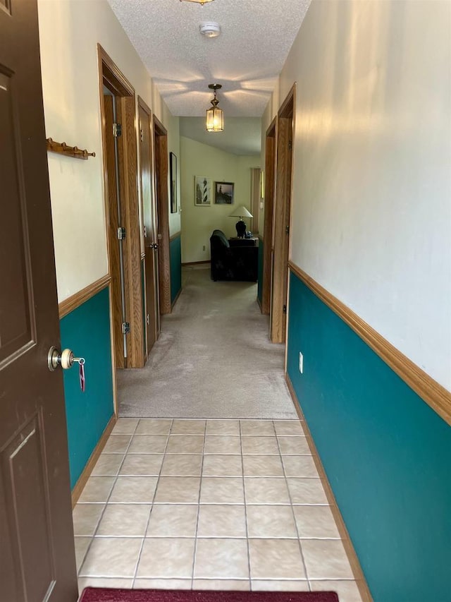 hall featuring light colored carpet and a textured ceiling