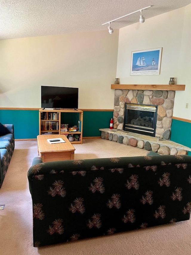 living room with rail lighting, a fireplace, carpet, and a textured ceiling