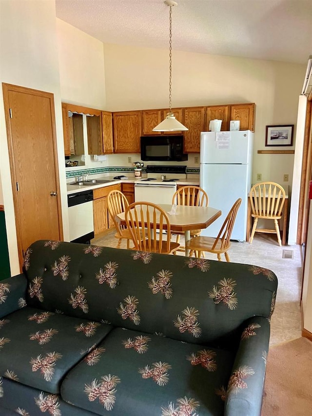 kitchen featuring light colored carpet, pendant lighting, white appliances, and high vaulted ceiling