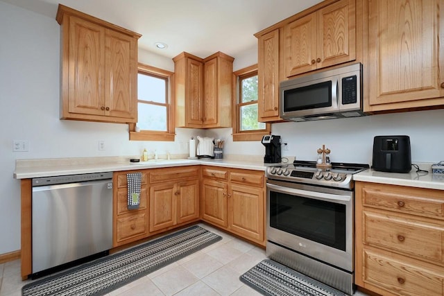 kitchen with light countertops, light tile patterned flooring, appliances with stainless steel finishes, and a sink