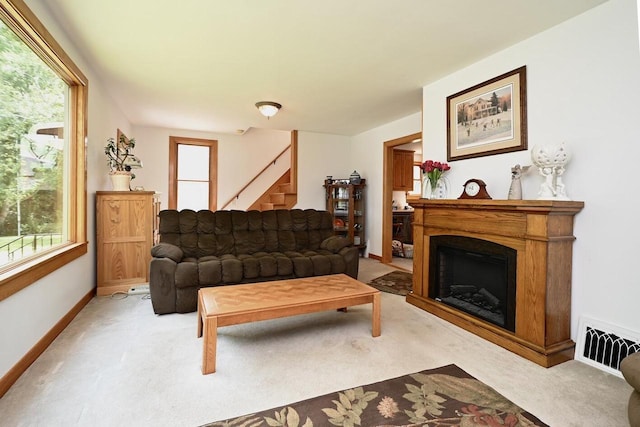 living room with visible vents, stairway, a fireplace, baseboards, and light colored carpet