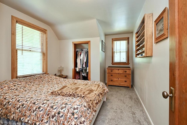 bedroom with a closet, baseboards, light colored carpet, a spacious closet, and vaulted ceiling