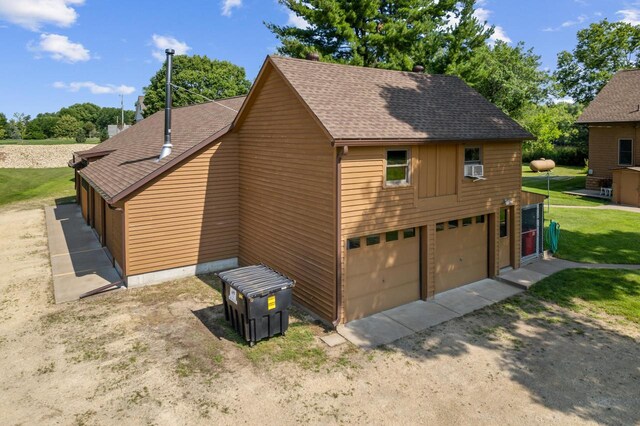 view of property exterior featuring a yard, roof with shingles, and driveway