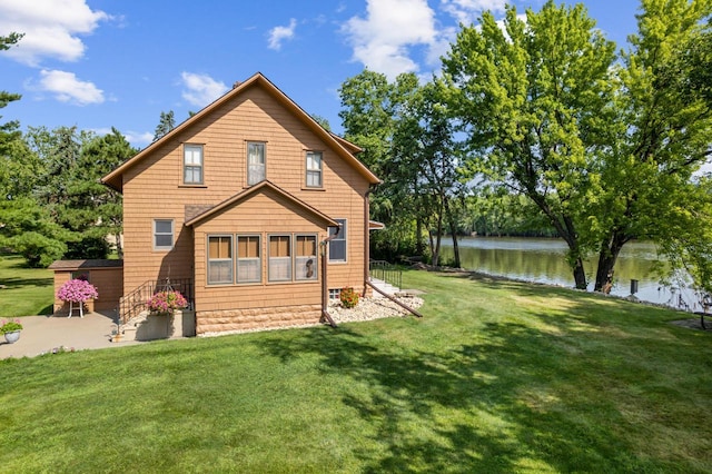 back of property with a water view and a yard