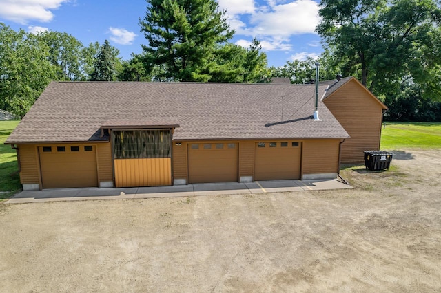 view of front of house featuring driveway, a shingled roof, and a detached garage