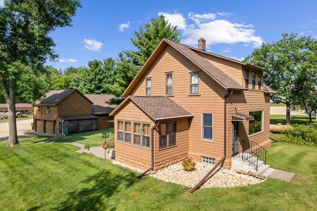 rear view of property with a garage, a chimney, a yard, and roof with shingles