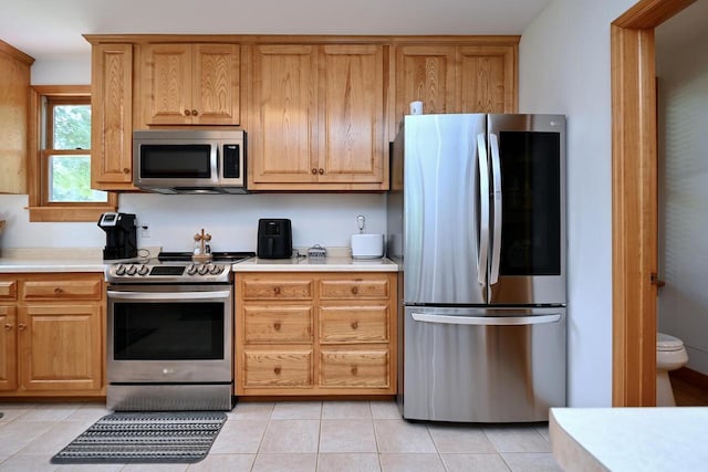 kitchen with light tile patterned floors, stainless steel appliances, and light countertops