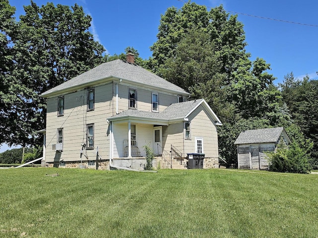 view of front of property featuring a front lawn, covered porch, and a storage unit