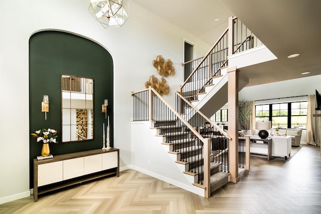 stairs featuring a chandelier, a high ceiling, and parquet floors