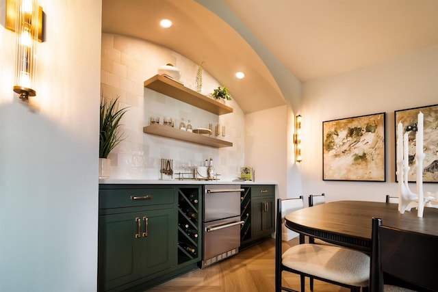 bar with decorative backsplash, green cabinets, and light parquet floors