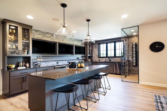 bar with brick wall, dishwasher, hanging light fixtures, and light hardwood / wood-style floors