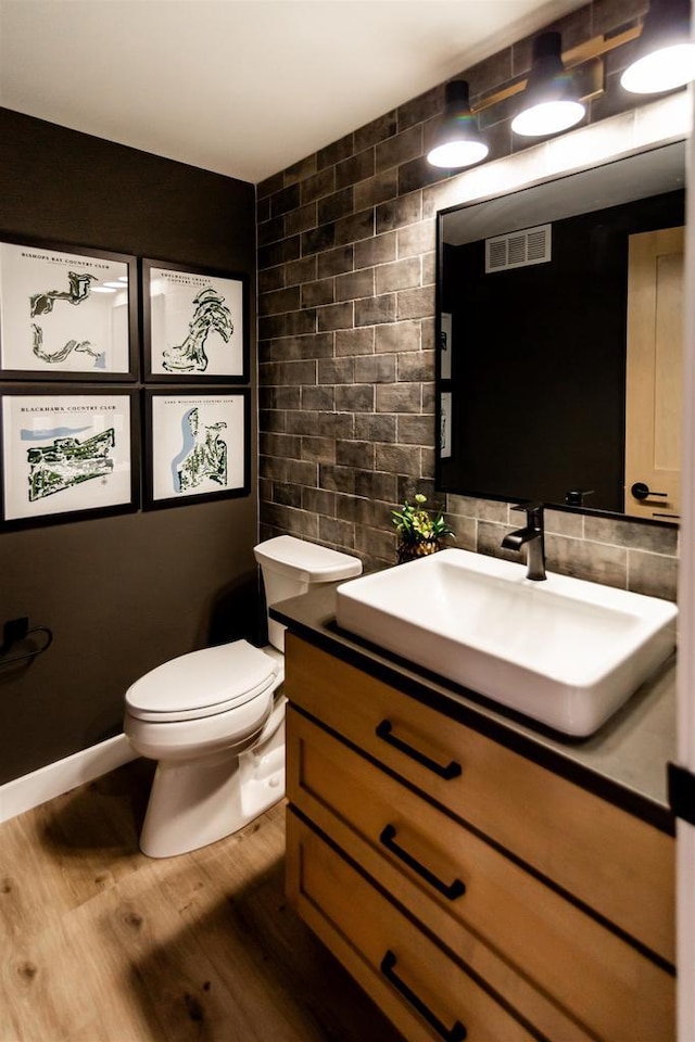 bathroom with backsplash, tile walls, vanity, toilet, and hardwood / wood-style flooring