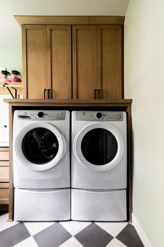 clothes washing area with cabinets and separate washer and dryer