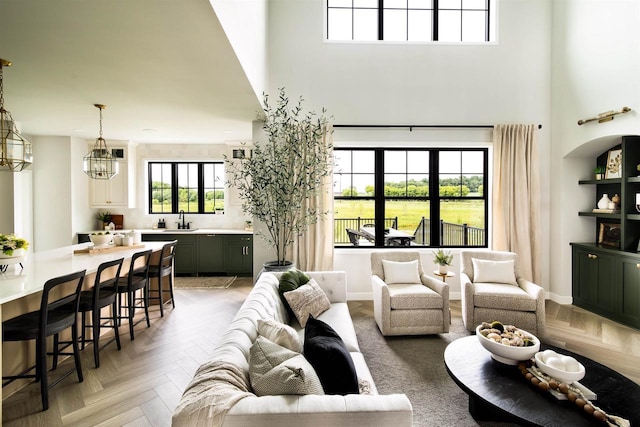 living room featuring sink, a high ceiling, parquet flooring, and an inviting chandelier