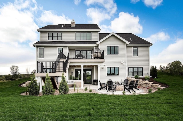 back of property with a lawn, a patio area, a balcony, and an outdoor fire pit