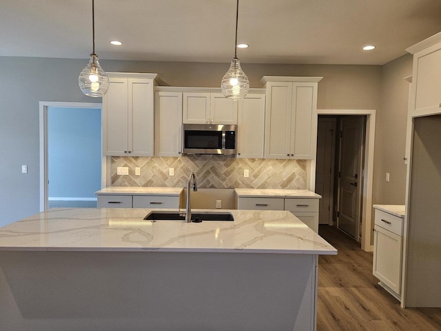 kitchen featuring a sink, stainless steel microwave, and white cabinetry