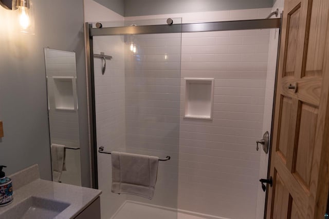 bathroom featuring a shower with door and vanity