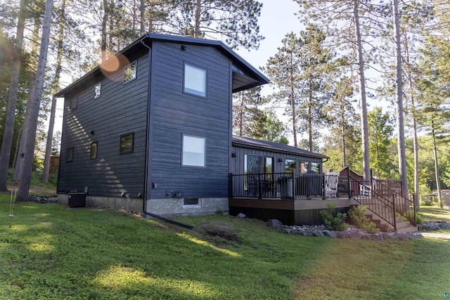 rear view of house featuring central AC unit, a deck, and a yard