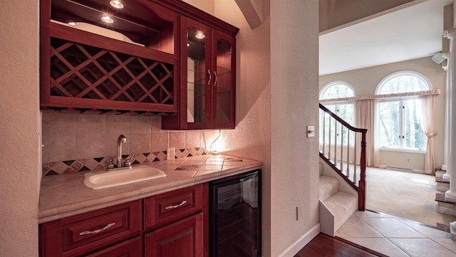 bar featuring tasteful backsplash, sink, hardwood / wood-style flooring, and beverage cooler