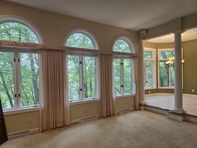 interior space with a baseboard radiator, a notable chandelier, and ornate columns